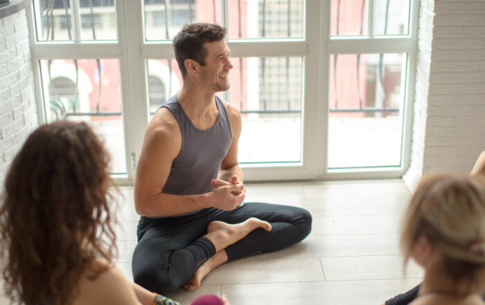 Mid aged attractive yogi sitting in circle sharing positive energy and emotions.