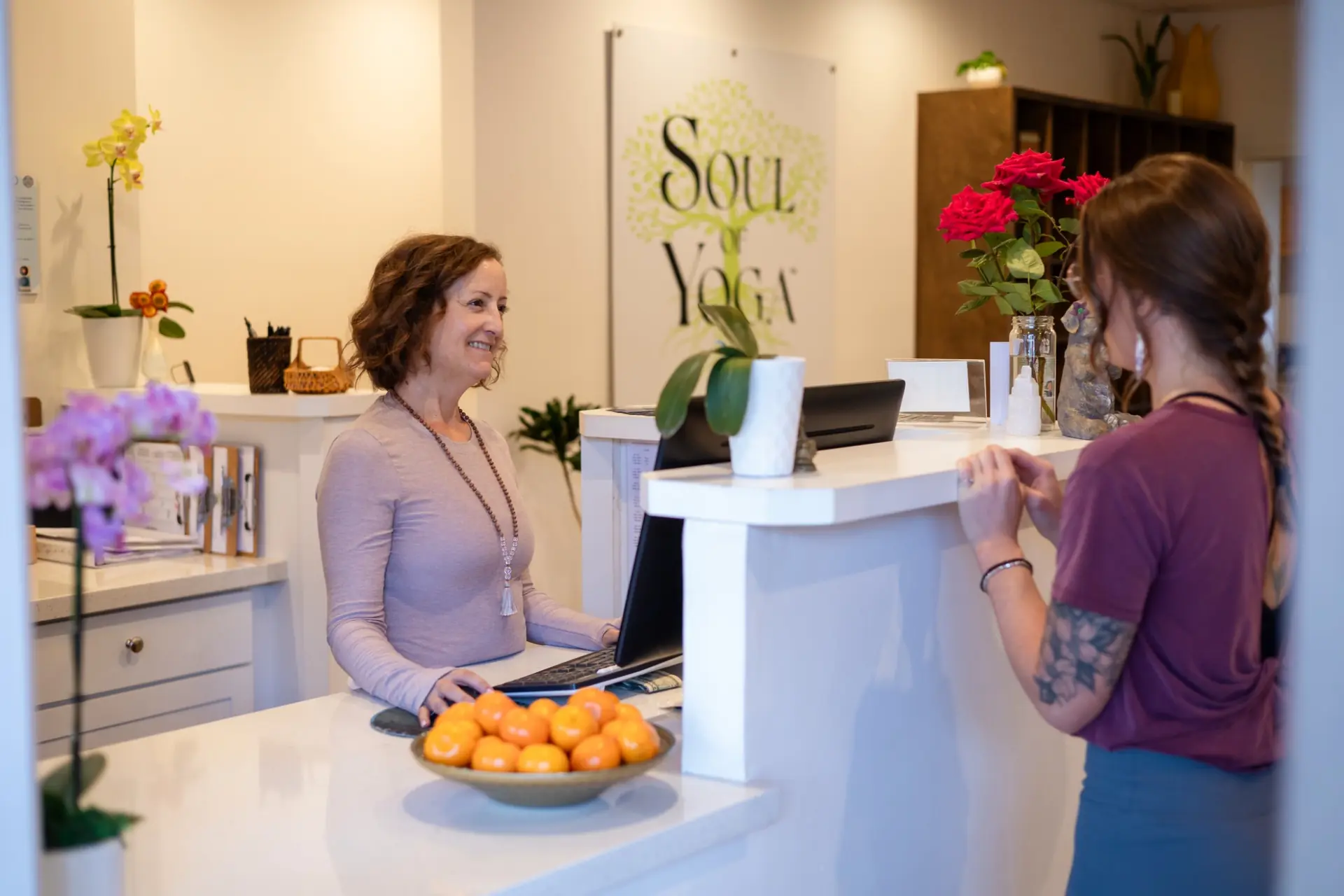 A visitor speaking with a team member at the Soul of Yoga front desk